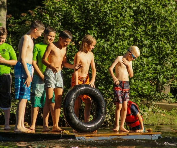 A group of returning campers explains a few lake games on the floating dock to new overnight campers.