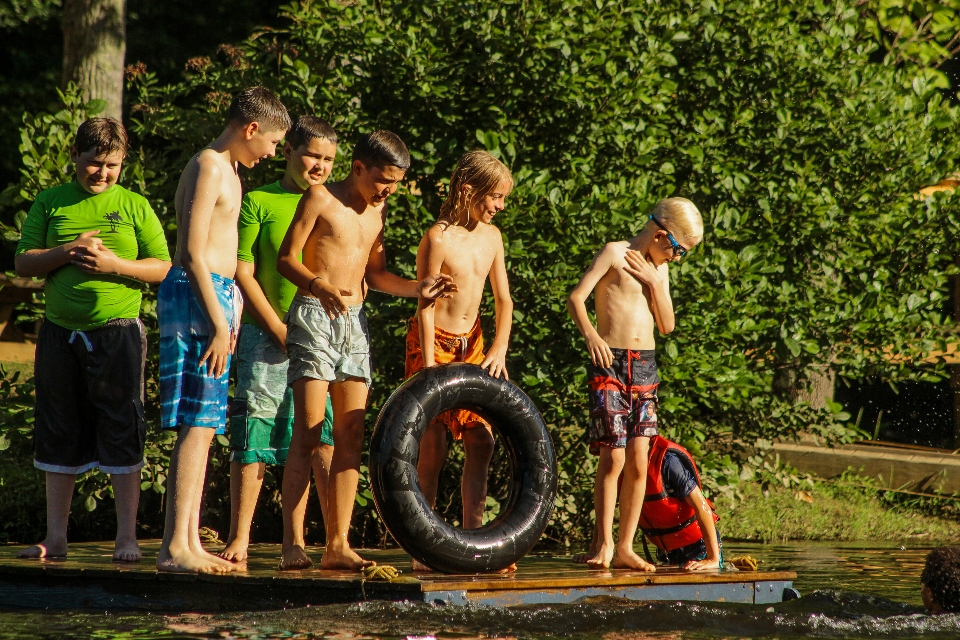 A group of returning campers explains a few lake games on the floating dock to new overnight campers.