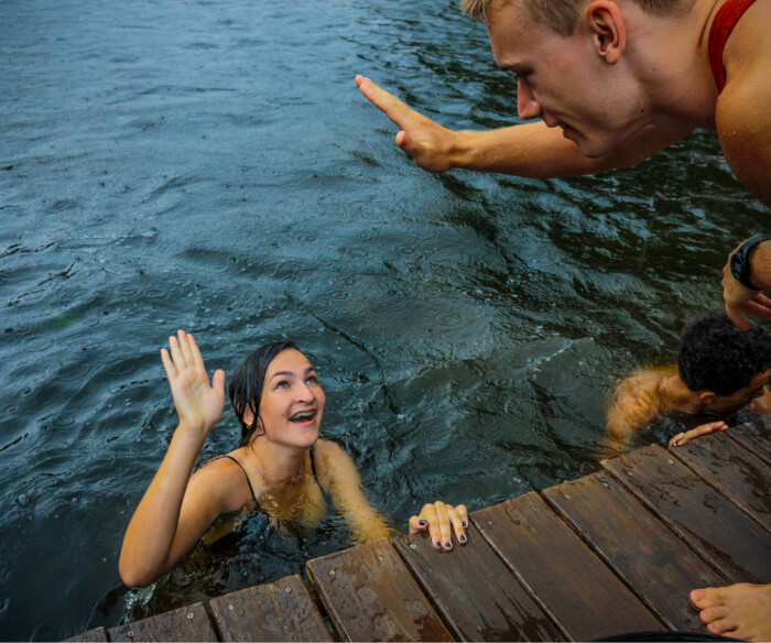 Teen girl camper and male counselor high five at Camp Friendship Lake