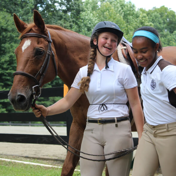 Two girls walking with horse at Camp Friendship Equestrian Center