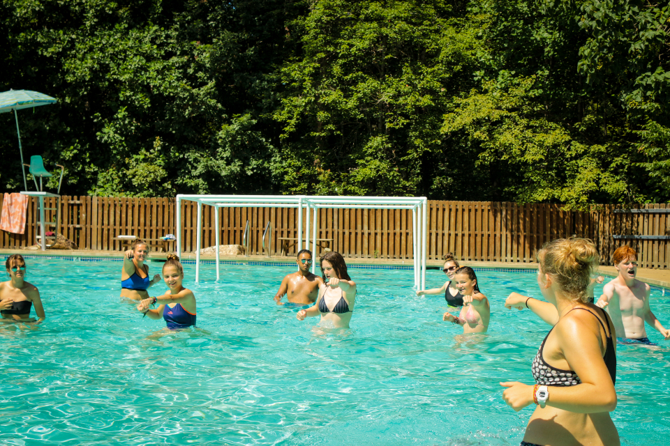 A counselor leads campers in the pool in a zumba workout.
