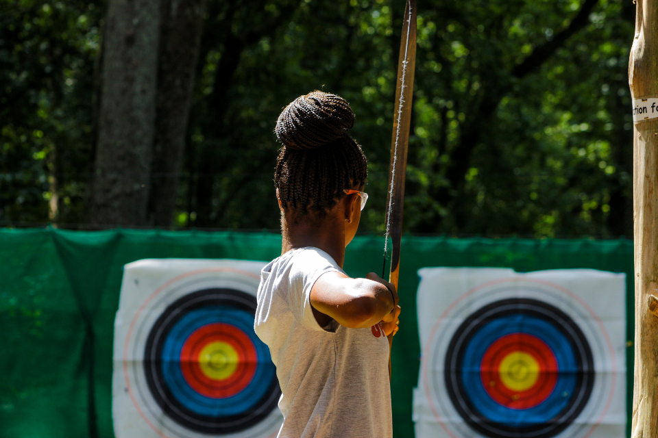 One of our teen campers aims down range with her bow as she lines up a bulls eye at our archery range.