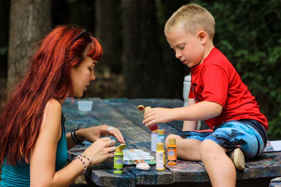 A female counselor helps a junior camper with their arts and crafts project during our overnight camp sessions.
