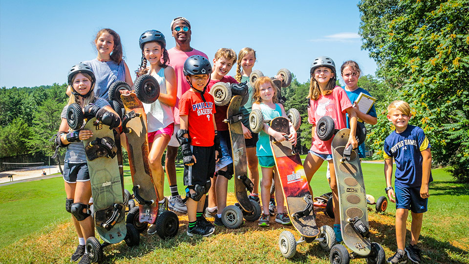 A group of coed junior campers poses with their mountain boards at the end of a lively activity.