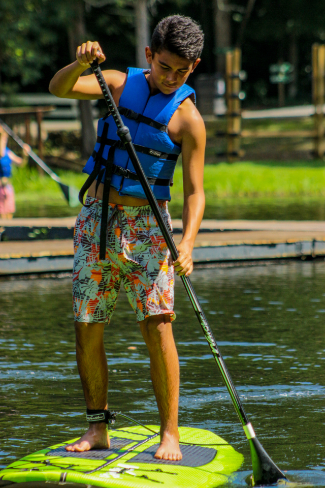 Teen boy paddle boards at Friendship Lake in Virginia