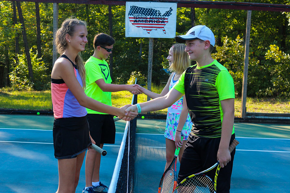 Coed campers shake hands after a tennis match at Camp Friendship summer tennis program