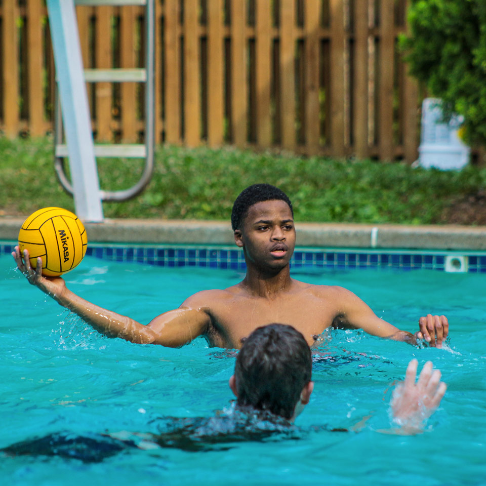 Boy ready to pass waterpolo ball in pool to a teammate