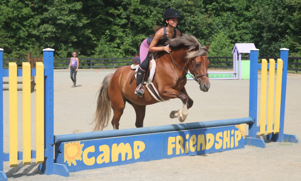 Equestrian Camper jumps with her horse at the Camp Friendship overnight horseback riding camp in Virginia