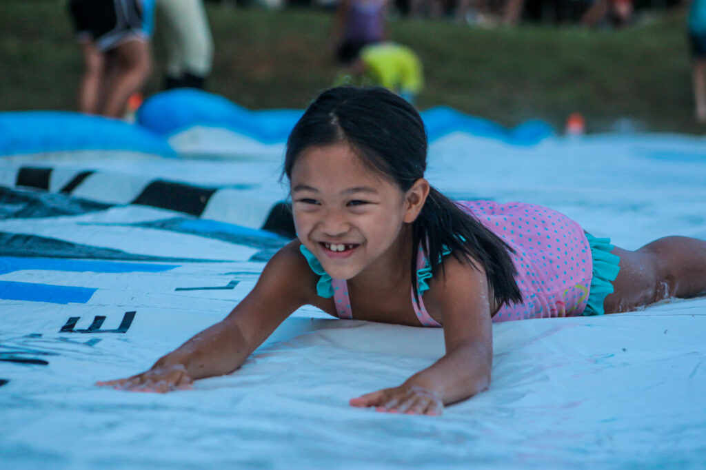 Junior girl camper on slip 'n slide at overnight camp in Virginia