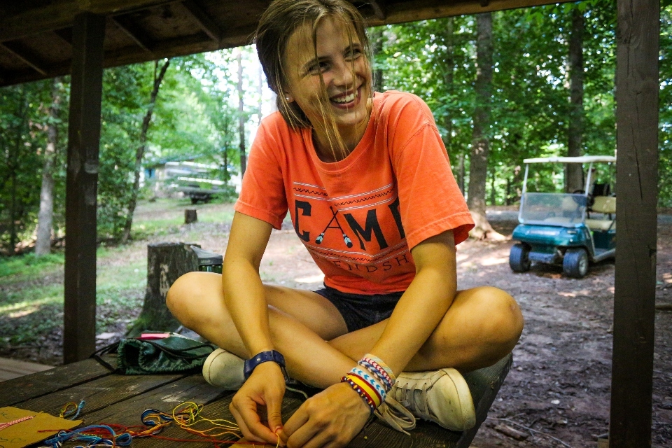 Teen girl camper learns how to make a friendship bracelet at an overnight camp in Virginia