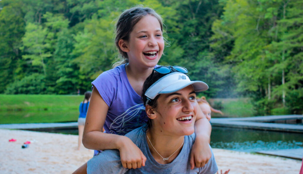 Camper and counselor having fun at Friendship Lake at overnight summer camp for kids and teens