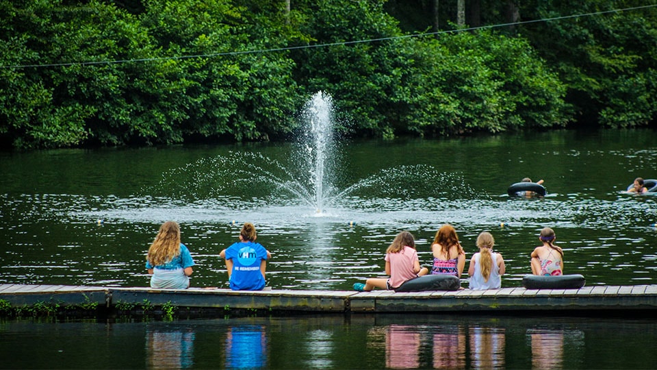 Campers on the lake dock in front of a fountain