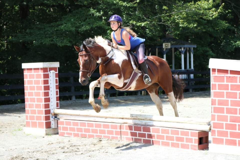 Equestrian camper jumps her horse in the Show Ring at the overnight horseback riding camp at Camp Friendship in Virginia
