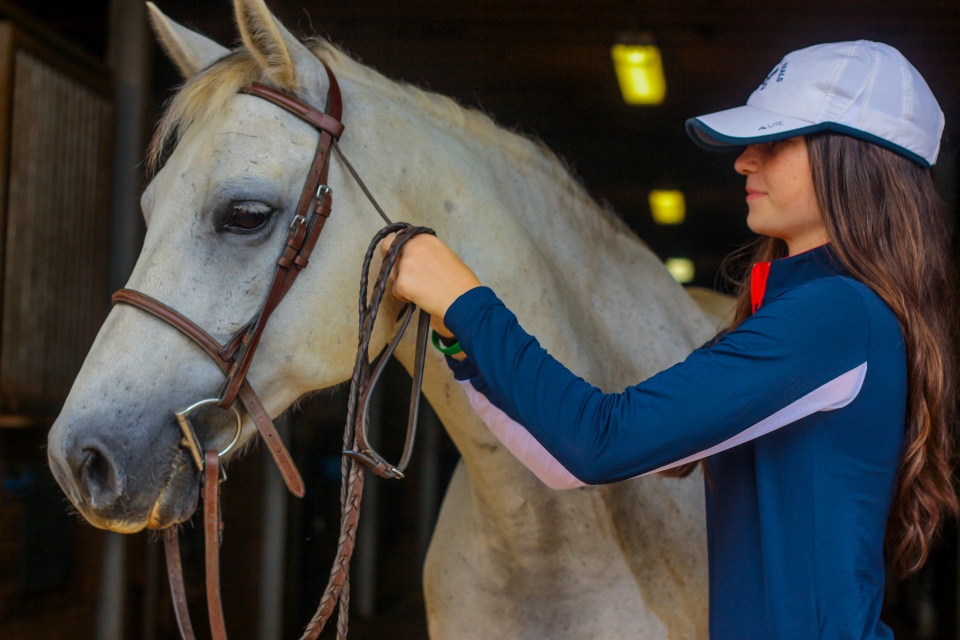 Equestrian camper puts a bridle on her horse at Camp Friendship Equestrian Center overnight camp in Virginia