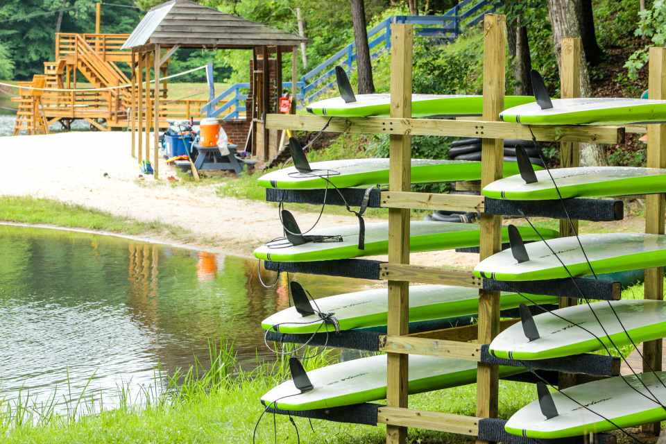 A rack of our green paddle boards stand ready to sail the water.
