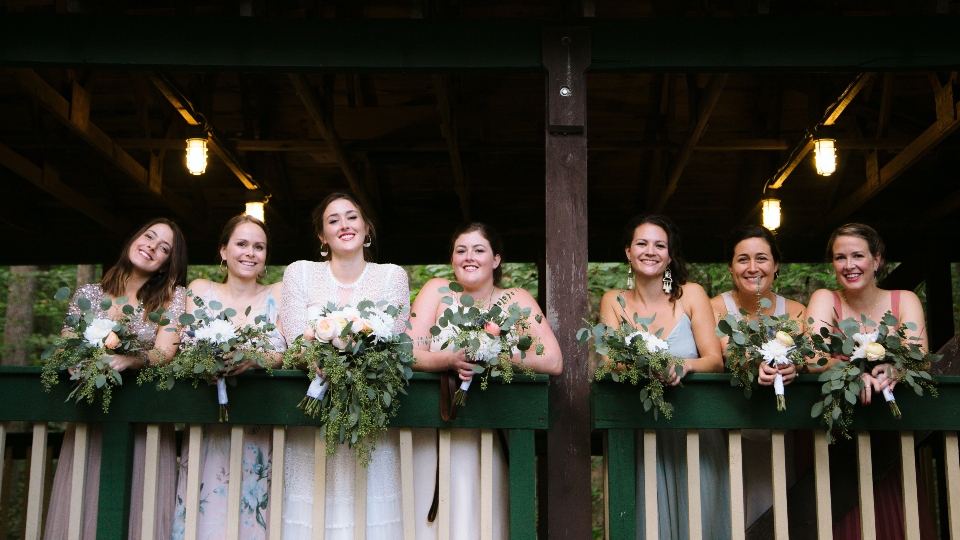 A bridal party poses with flowers in our dance pavilion as they prepare for a camp wedding ceremony.
