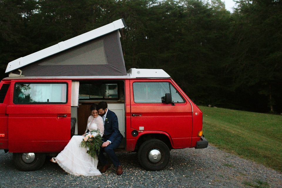 A Bride and Groom sitting in a parked red volkswagen van