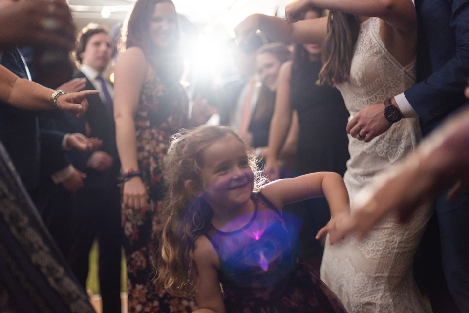 A young girl dances with family in the middle of the post camp wedding reception.