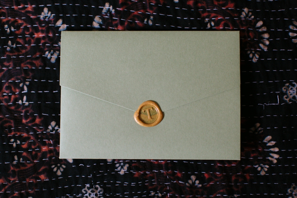 a sealed wedding invitation, sealed with gold wax.