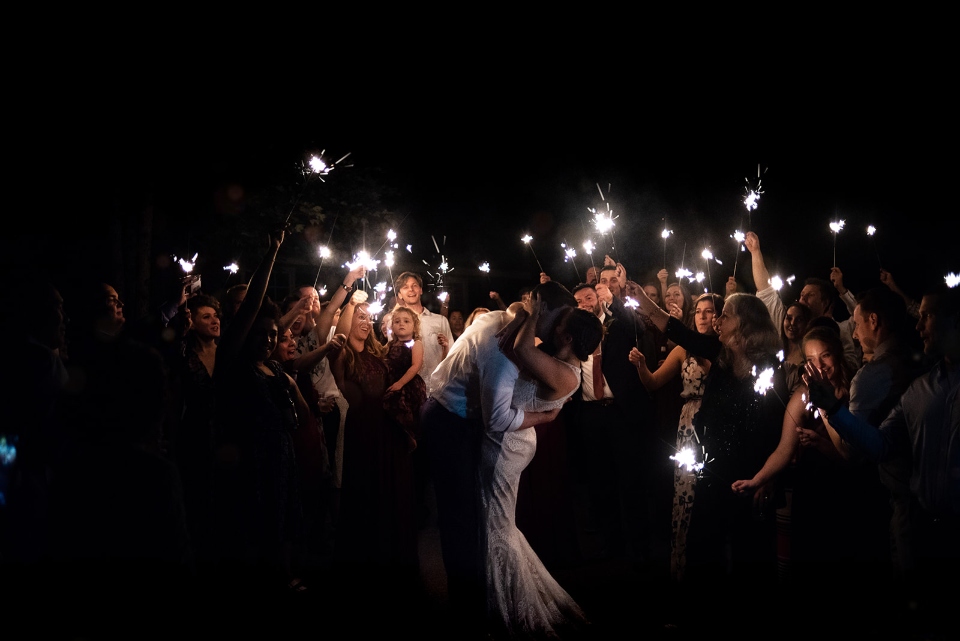A wedding party celebrates the night with sparklers and smiles in one of our summer camp villages.