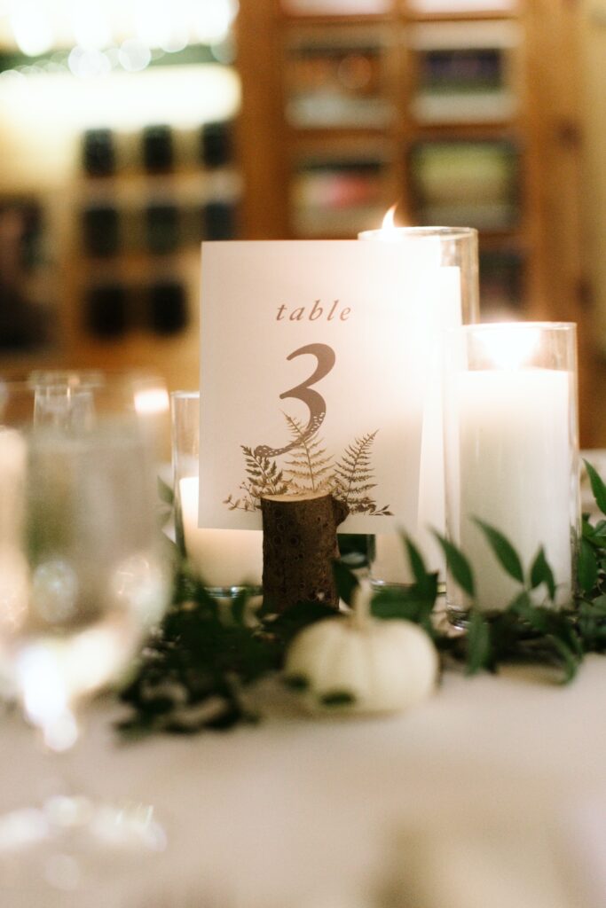 A tasteful candle center piece and table number decorate one of our camp wedding meal layouts.