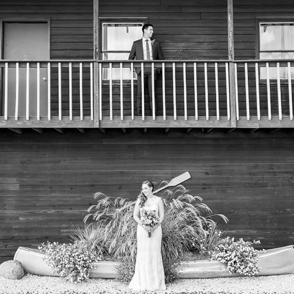 Groom standing on second floor balcony and bride standing below waiting to have their first look at Virginia wedding venue