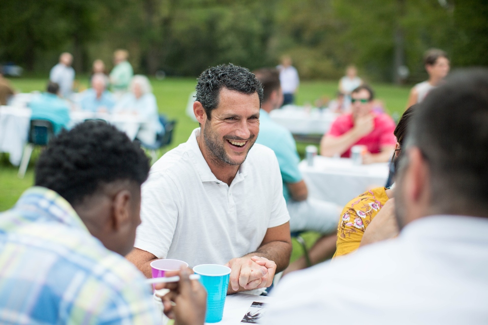 Men enjoying food and conversation during outdoor Wedding Reception meal