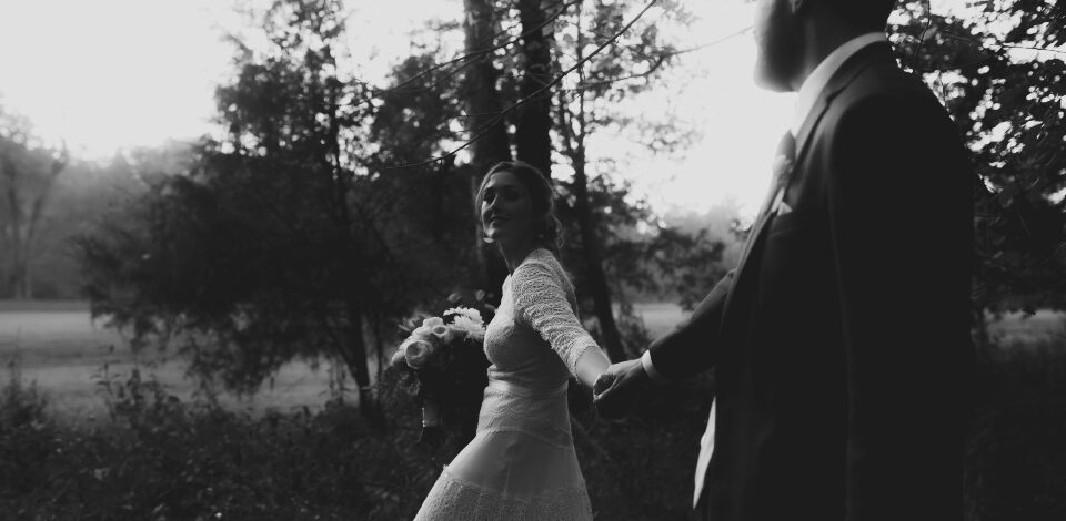 Bride holding grooms hand; leading him through the woods at Virginia Wedding venue