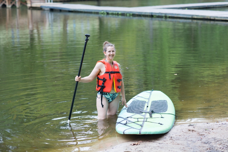 Woman in lifejacket with paddle getting ready to paddle board at a retreat at Camp Friendship in Virginia