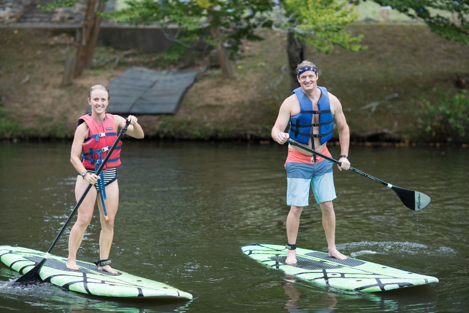 Man and Woman paddle boarding on the lake at Camp Friendship wedding venue