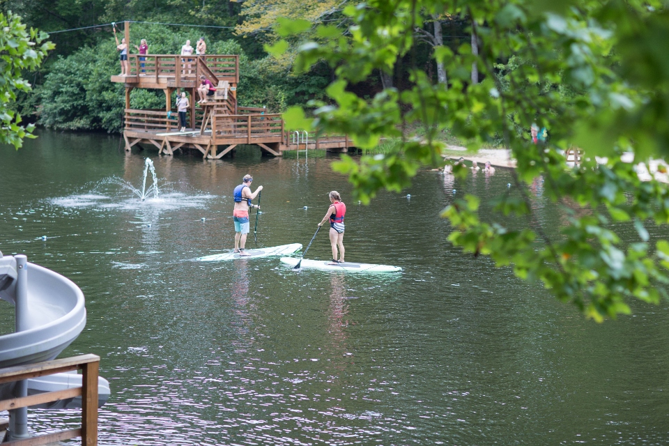 Two people paddle boarding on the lake at Camp Friendship