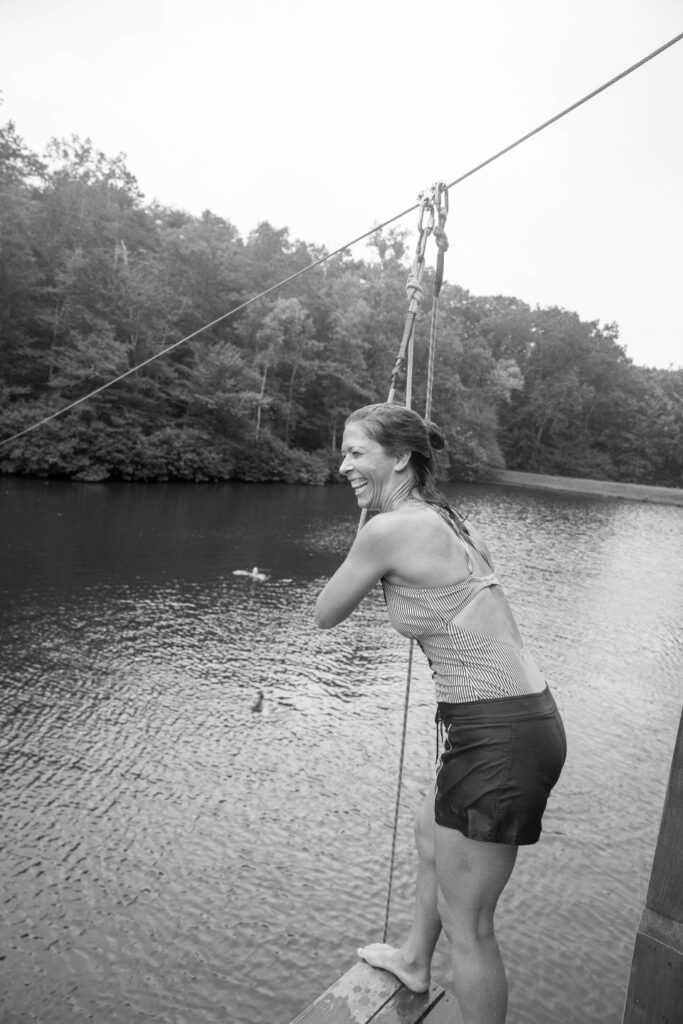 Woman getting ready to zipline into lake at Camp Friendship