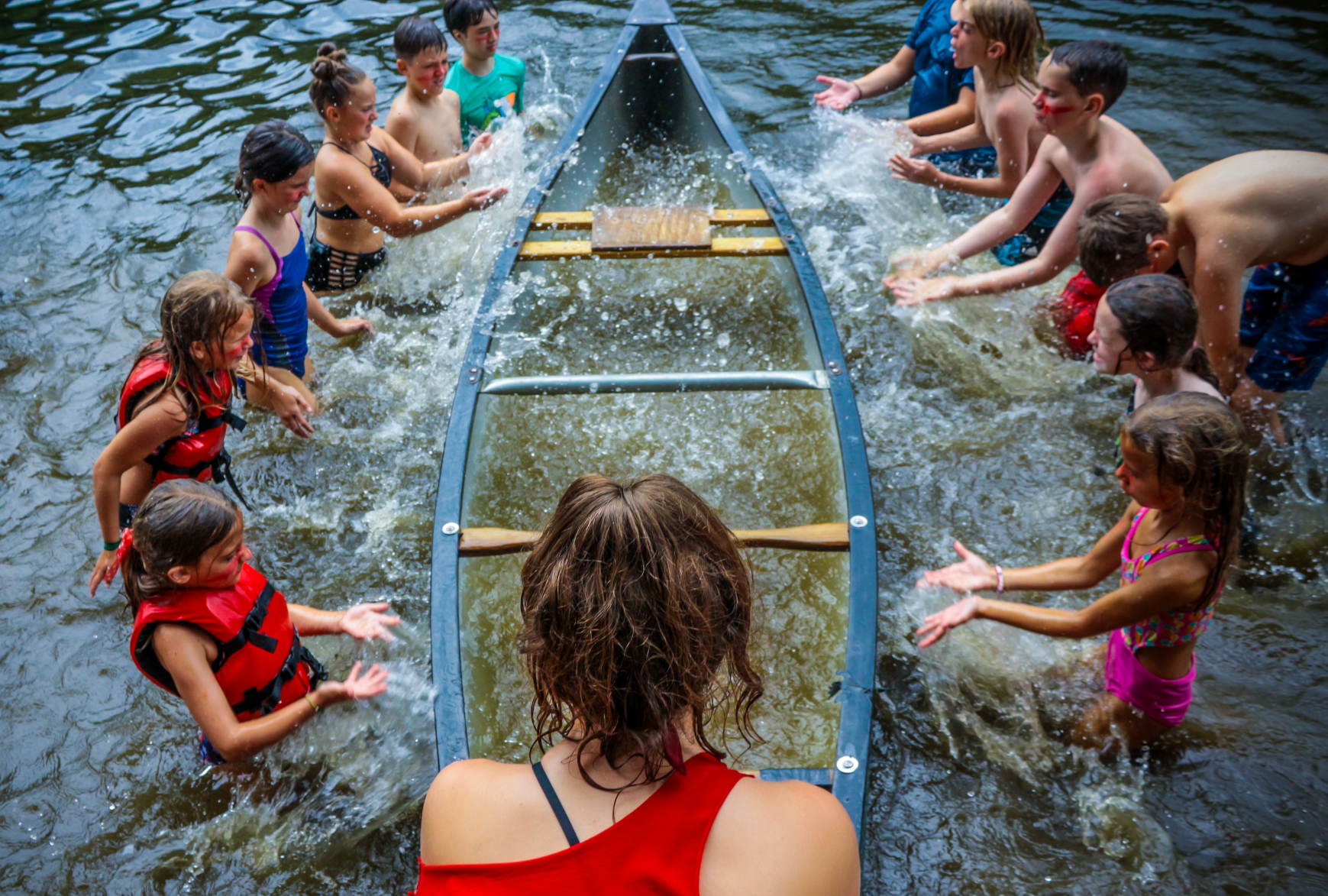 Campers splashing water into a canoe during a Color Wars event