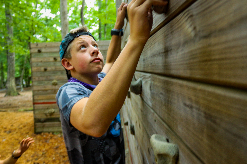 A teen camper works his way sideways on our bouldering wall.