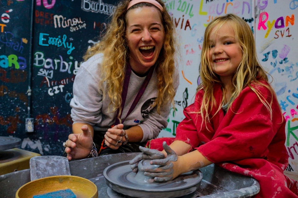 Counselor teaches pottery to a young girl at Family Camp