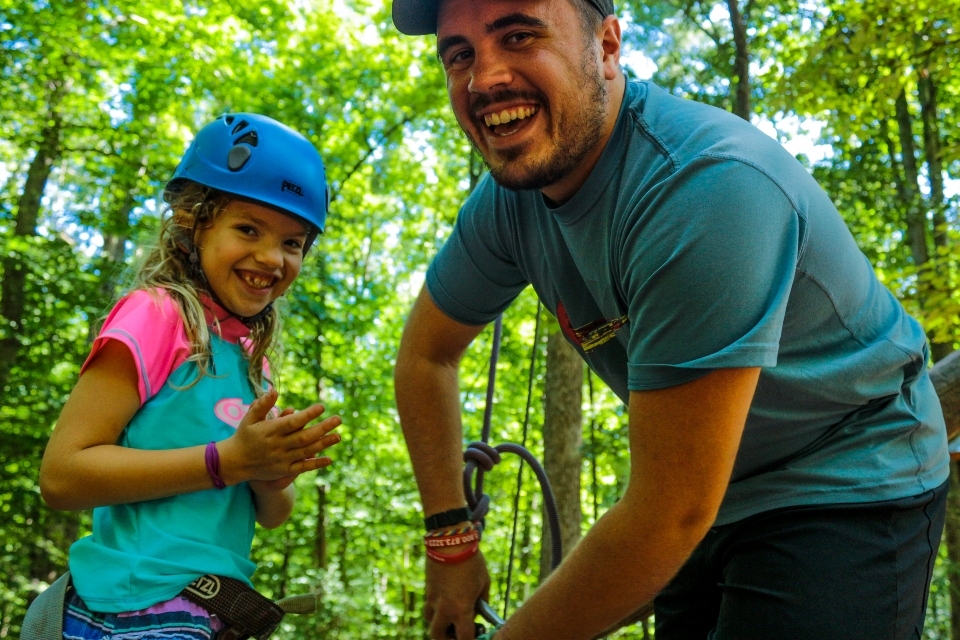 Junior Girl  camper and Male staff getting ready to climb at high ropes course in Virginia