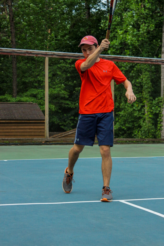 Senior village boy swings his racket at Camp Friendship summer tennis camp in Virginia