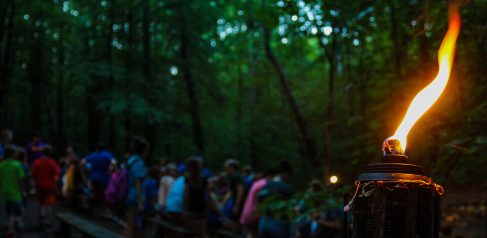 A tiki torch illuminates our overnight camp getting ready for an evening of performances, skits, and songs at campfire.