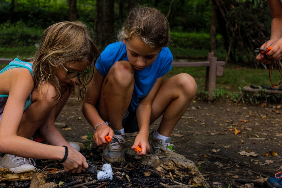 Two girls learning fire building as an activity at Camp Friendship