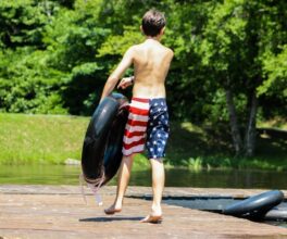 A camper walks across the dock on Friendship Lake with an inner tube ready for fun.
