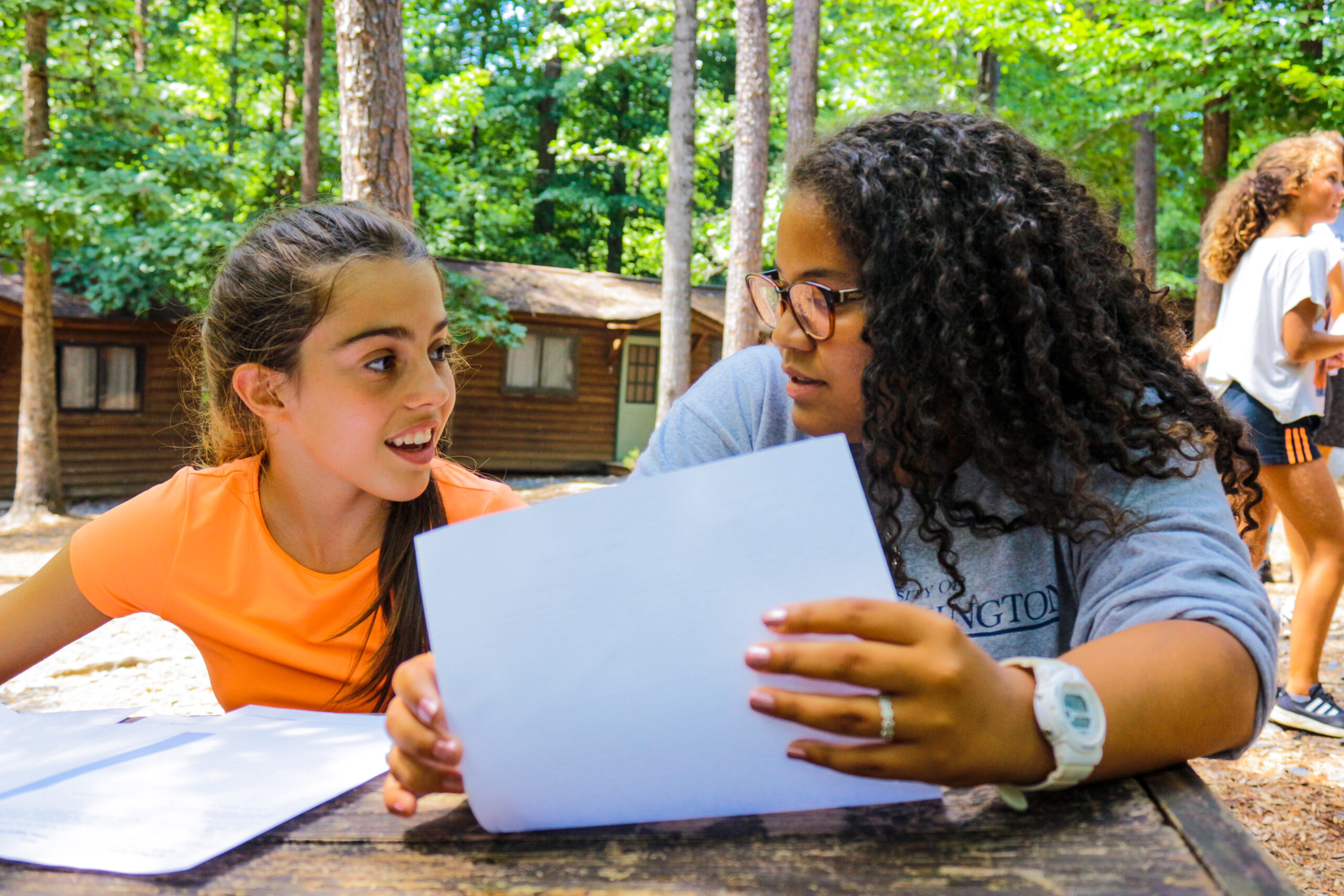 Camp counselor showing a girl a piece of paper.