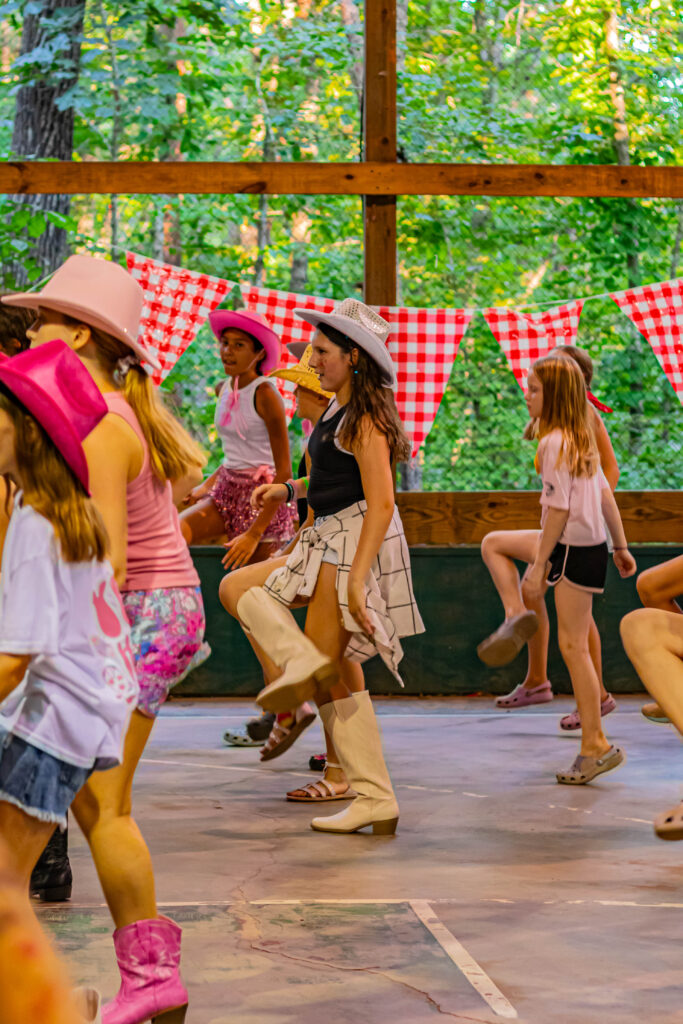 Side view of people dancing in rows with cowboy outfits on