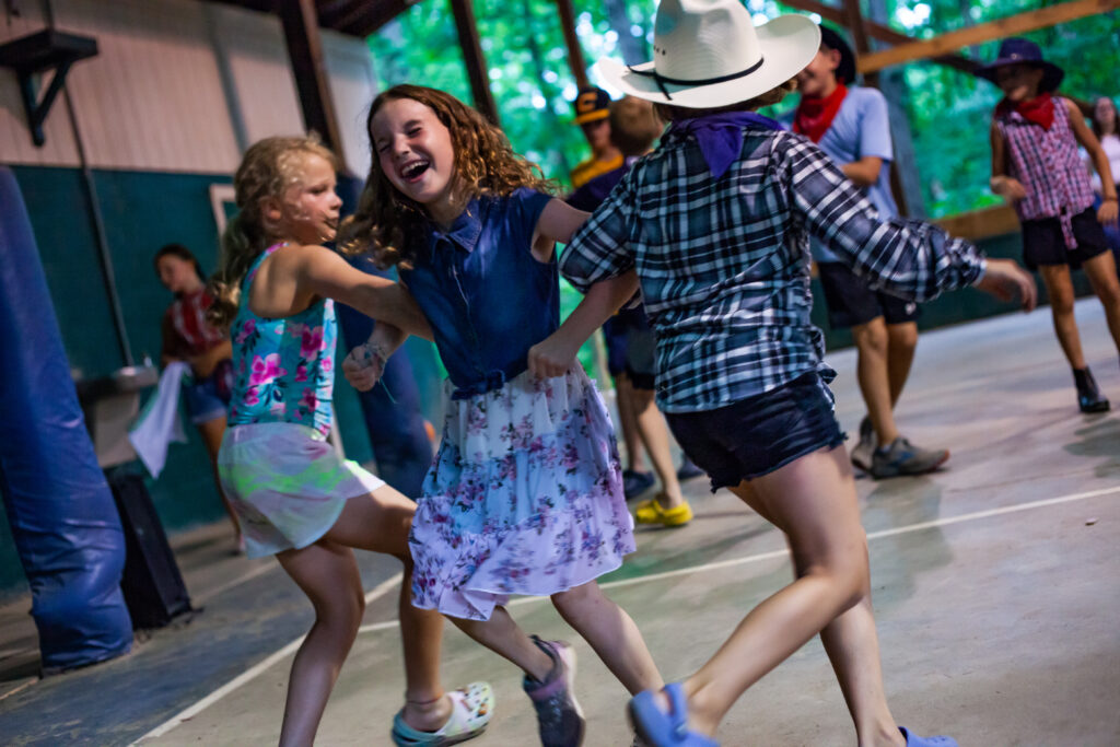 3 girls interlocking their arms and dancing 