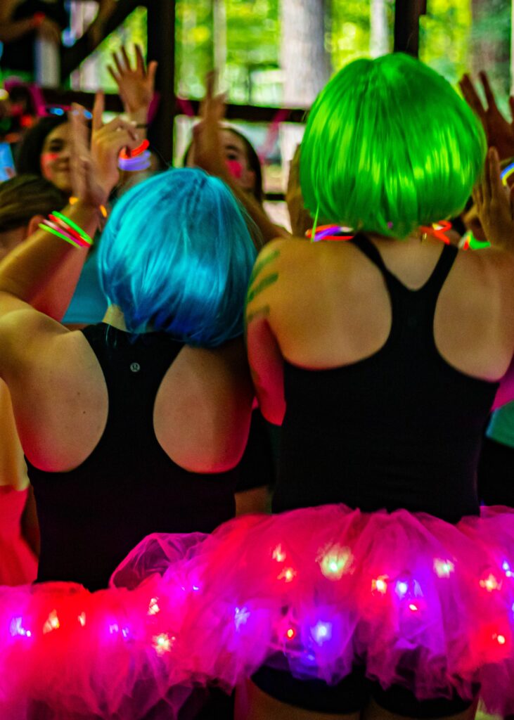 Row of 2 girls turned around wearing colorful bob wigs