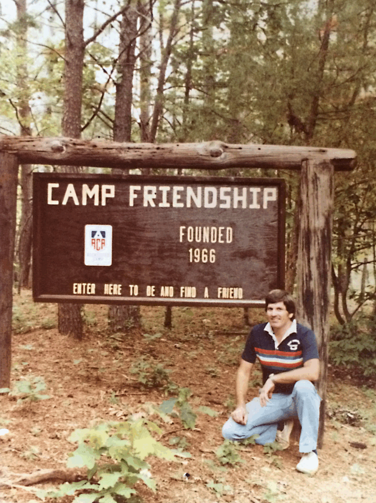 A sepia photo of a man crouched next to the Camp Friendship entrance